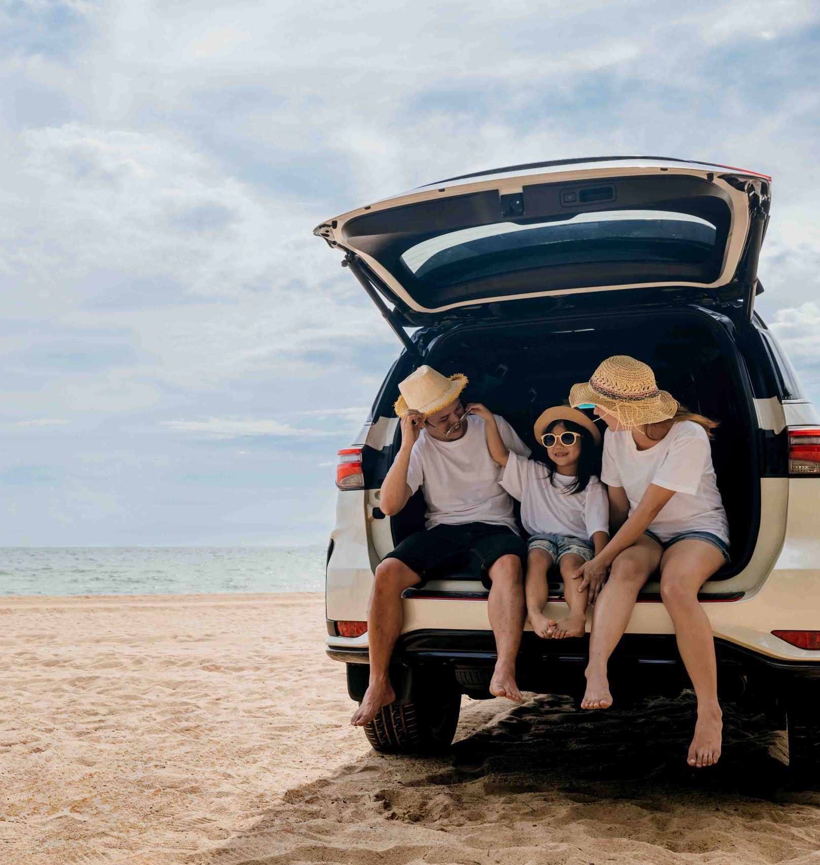 Family sitting out the back of car on the beach